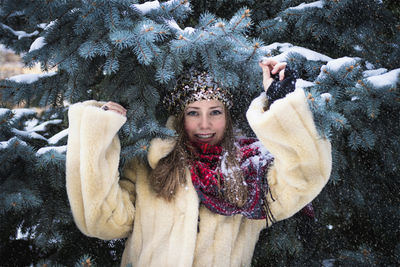 Portrait of woman standing against trees during winter