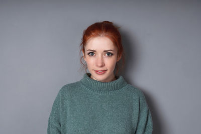 Portrait of young woman standing against wall