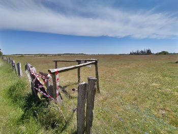Wooden fence on field against sky