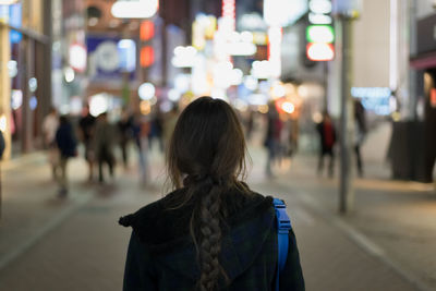 Rear view of woman walking on street at night