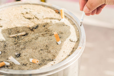 Cropped image of hand holding cigarette over ashtray