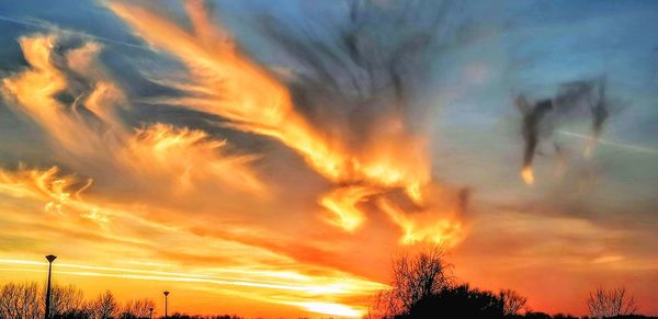 Low angle view of silhouette trees against dramatic sky