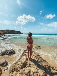 Rear view of woman on beach against sky