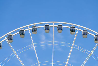 Low angle view of ferris wheel against clear blue sky