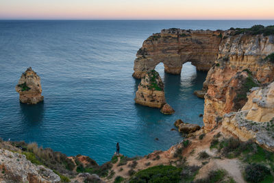 Woman in natural arch cliffs of praia da marinha beach at sunset in lagoa portugal