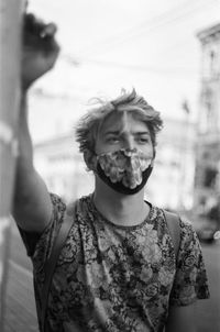 Low angle view of a man wearing a mask and standing against buildings