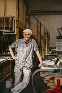 Portrait of smiling craftsman with hand on hip at workshop