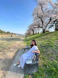 Young woman sitting on field against clear sky