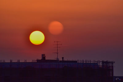 Silhouette built structure against orange sky