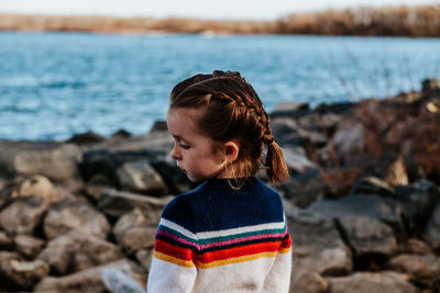 Portrait of young girl looking away on rocks at a lake