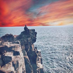 Rock formation on sea against sky during sunset