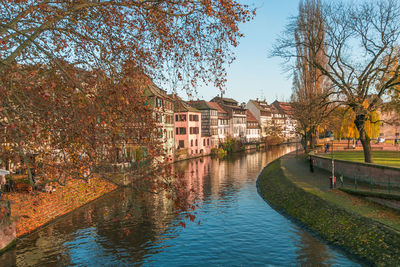 Buildings by river against sky during autumn