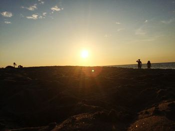 Silhouette people on landscape against sky during sunset