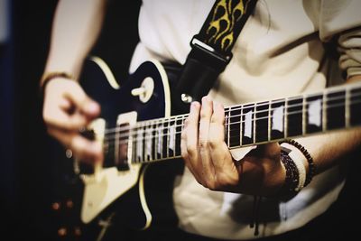 Midsection of man playing guitar