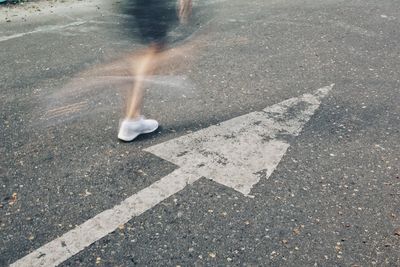 Low section of man running by arrow road sign 