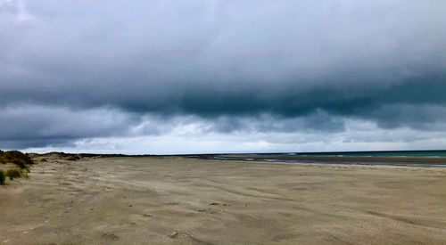 Scenic view of beach against cloudy sky