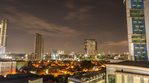 Illuminated buildings in city against sky