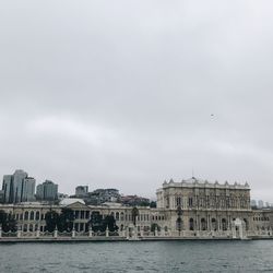 View of buildings by river against cloudy sky