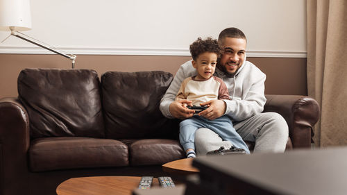 Portrait of a smiling young man sitting on sofa at home