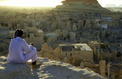 Rear view of man sitting on rock