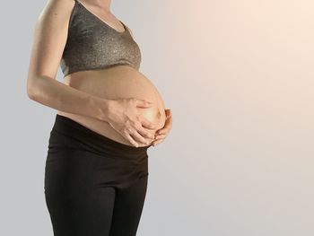 Midsection of woman touching face against white background