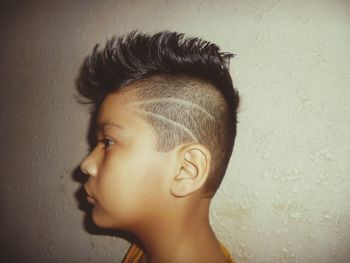 Profile view of boy standing by wall at home