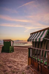 Hooded beach chair on sand against cloudy sky