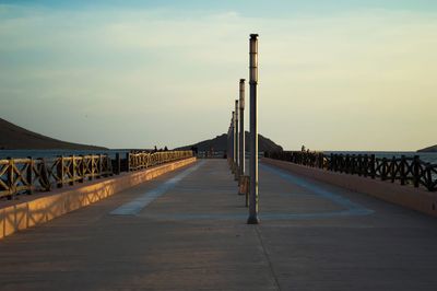 Empty bridge against sky during sunset