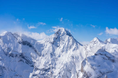 Scenic view of snowcapped mountains against blue sky