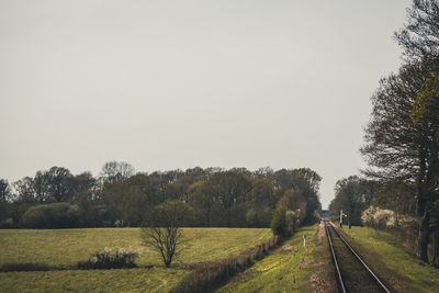 Railroad track amidst field against clear sky