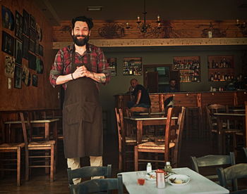 Portrait of young male barista standing in cafe