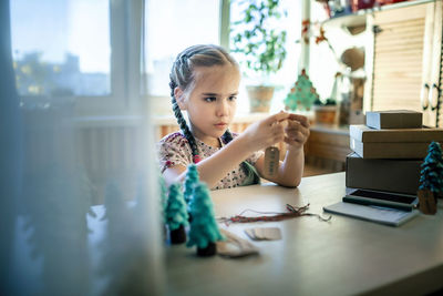 Girl preparing diy gifts and signing tags to family for christmas, handmade, zero waste holidays