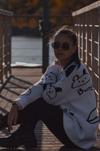 Portrait of young woman wearing sunglasses while sitting on chair