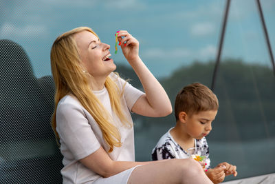 Happy blond woman and little boy sitting on terrace and eating sweets. mother and son enjoy