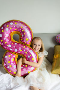 Portrait of girl with balloon lying on bed at home