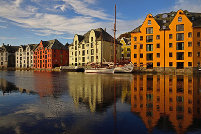 Residential buildings by river against sky