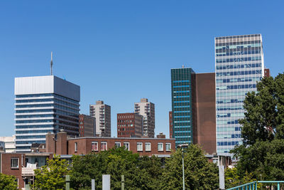 Buildings in city against clear blue sky