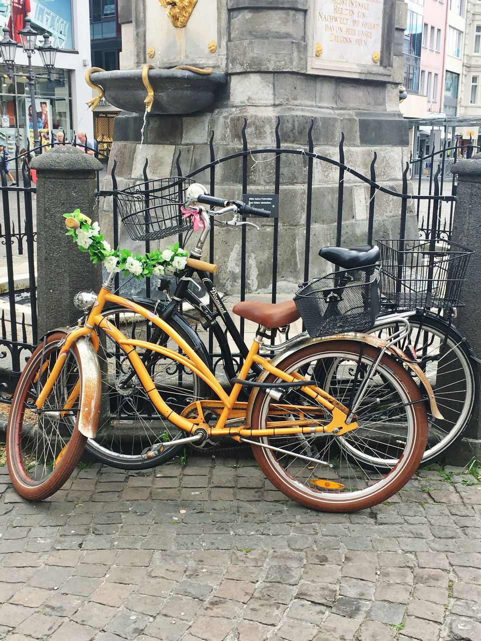 BICYCLE PARKED ON WALL BY STREET