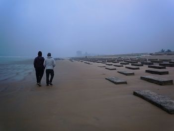 Rear view of people walking on beach