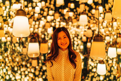 Portrait of woman standing against illuminated lights
