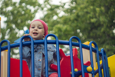 Full length portrait of boy standing on slide at playground