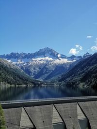 Scenic view of lake by snowcapped mountains against blue sky