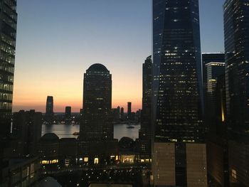 Illuminated buildings in city against sky at dusk