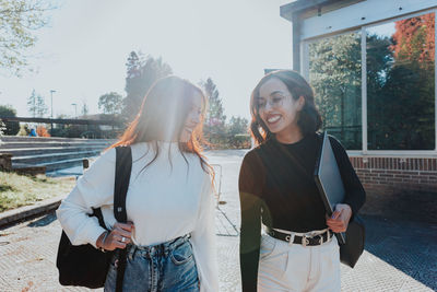 Smiling female friends walking together on sunny day