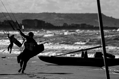 Silhouette man kiteboarding at beach during sunny day