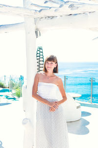 Portrait of smiling young woman standing against sea