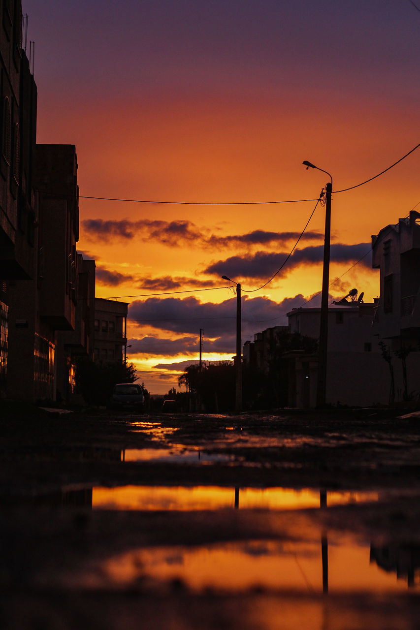 SILHOUETTE OF CITY STREET AGAINST ORANGE SKY