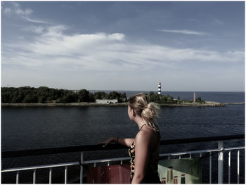 Woman standing by railing against sky