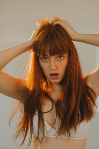 Portrait of young woman looking away against wall