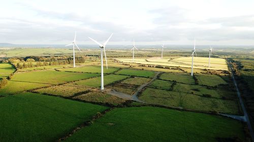 Windmills on field against sky